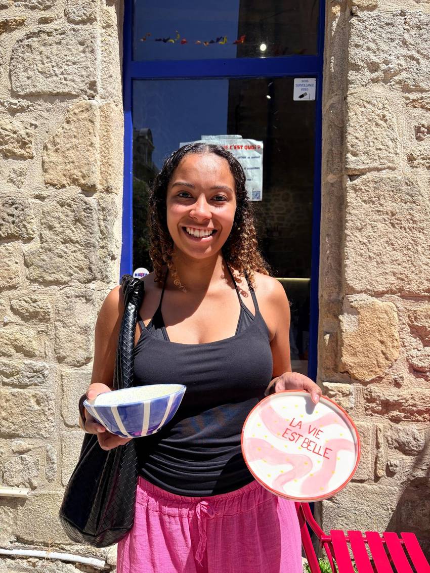 Cliente devant la façade en pierre et la porte bleue de KALON